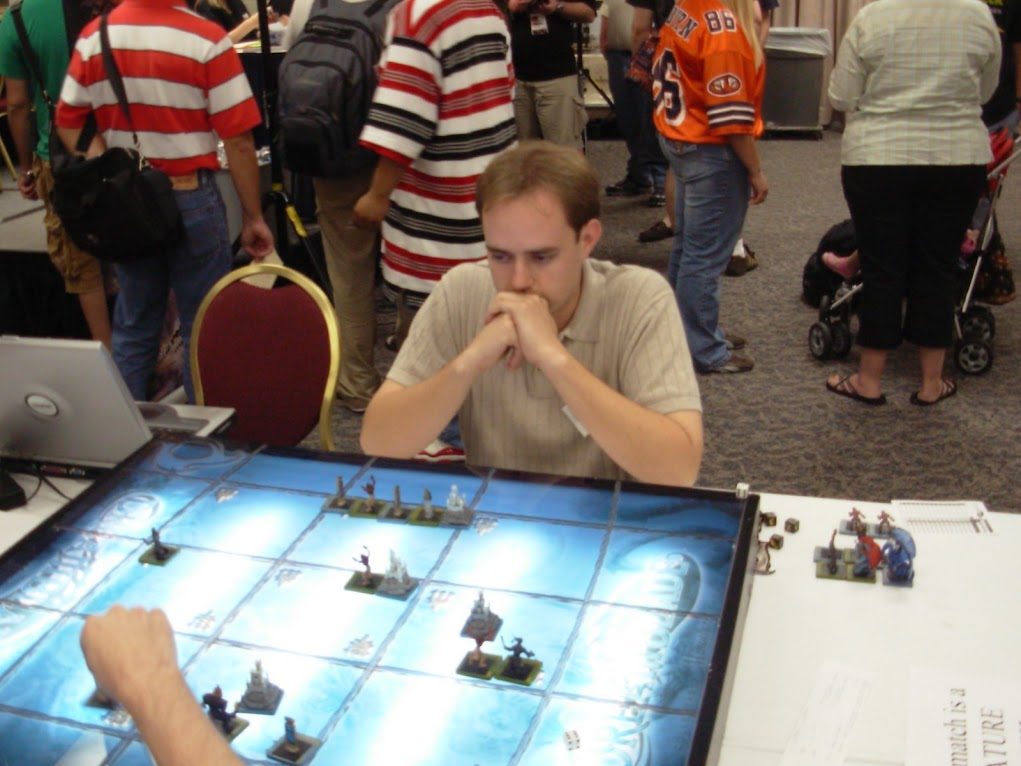 Mid-match concentration over a lit miniatures battle map at a convention